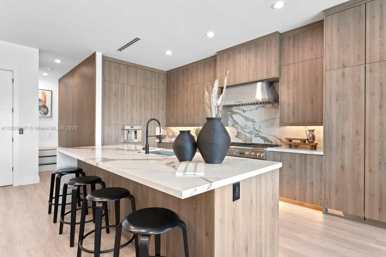 Contemporary IQ+ Cabinetry kitchen with wood cabinetry, marble island and pendant lighting in Tampa Bay