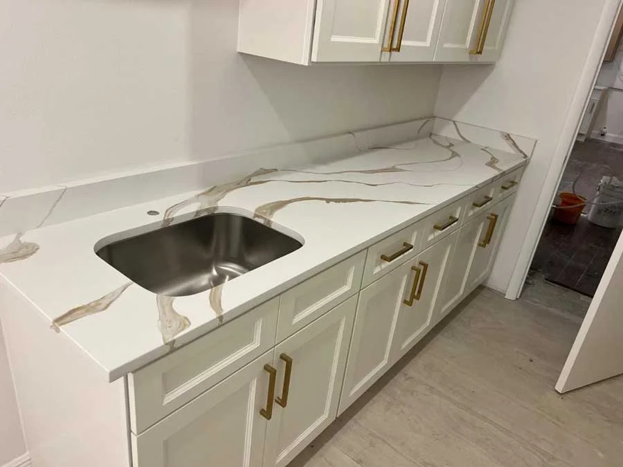 Modern white cabinetry with gold hardware, topped by a white m